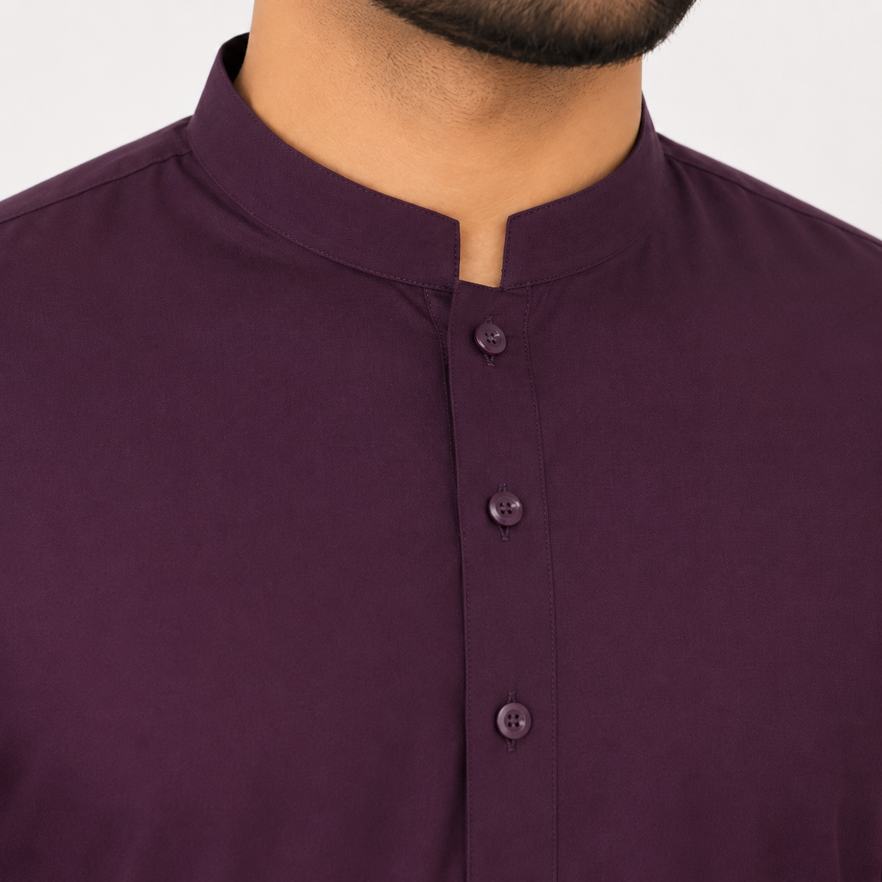 Close-up of a man wearing a dark plum purple kurta with a stand collar and three front buttons.