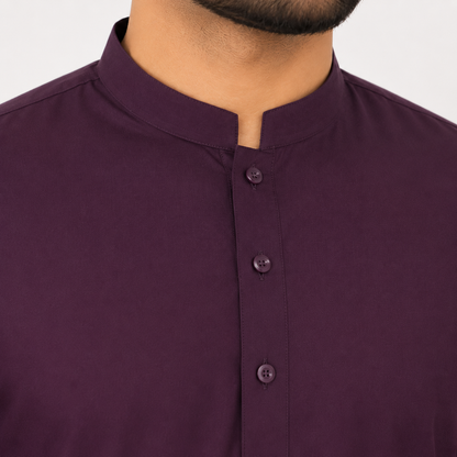 Close-up of a man wearing a dark plum purple kurta with a stand collar and three front buttons.