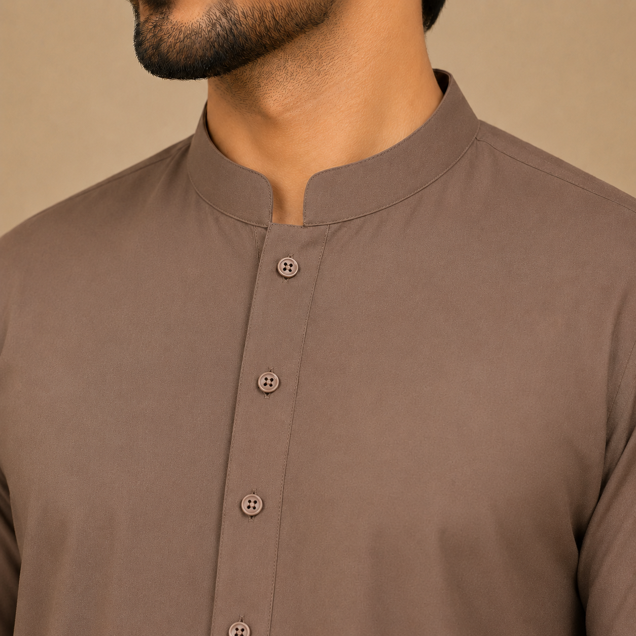 Close-up of a man wearing a taupe brown long-sleeve kurta with a mandarin collar and matching buttons.